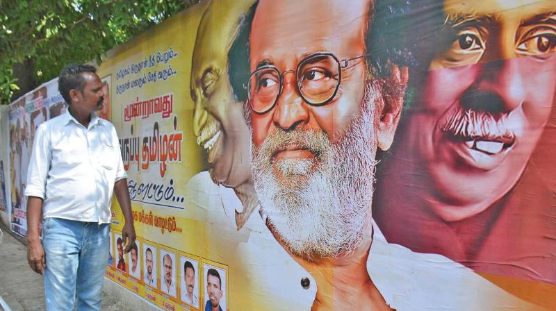 Rajinikanth fan looks the posters of the superstar sandwiched between the former Chief Ministers K. Kamaraj and C.N. Annadurai near his residence Poes Garden to mark the birthday celebrations of the actor on Tuesday. (Photo: DC)
