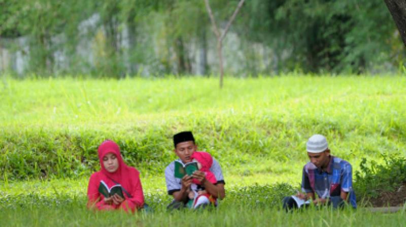 Family members gather to pray for their loved ones at a mass grave in Aceh. (Photo: AFP)