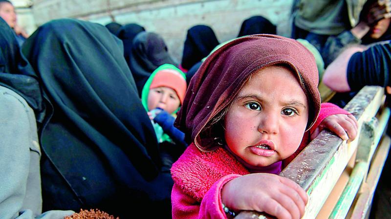 Women and children fleeing from the last Islamic States tiny pocket in Syria sit in the back of a truck near Baghuz, eastern Syria, on Monday. AFP