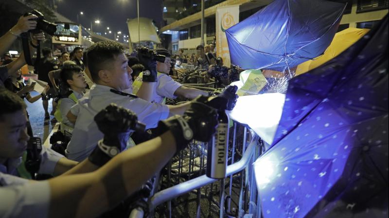 Protesters use umbrellas to block the pepper spray from police officers after clashing outside the Chinese central governments liaison office as thousands of people march in a Hong Kong on Sunday. (Photo: AP)