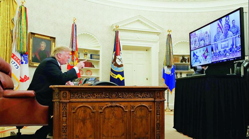 US President Donald Trump speaks with members of the five branches of the military by video conference on Christmas Day on Tuesday, in the Oval Office of the White House. The military members were stationed in Guam, Qatar, Alaska, and two groups in Bahrain. 	 AP