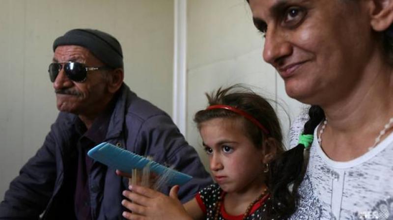 Christina sits between her blind father and her mother in their camp dwelling in north Iraq on Jun 10, 2017. (Photo: AFP)