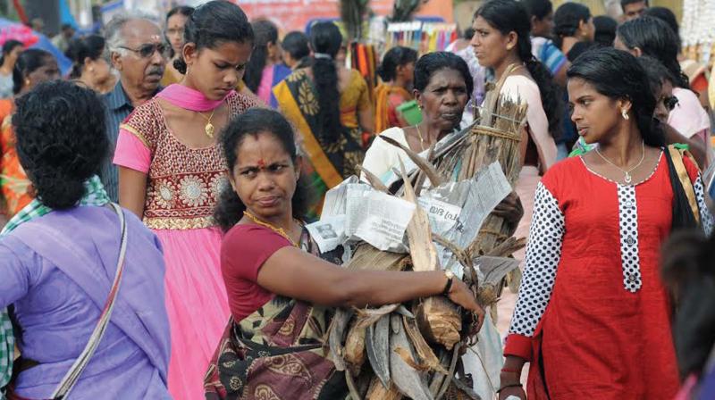 A devotee carrying firewood, dry palm leaves for lighting the hearth; devotees occupy space near the temple  premises on the eve of Attukal Pongala festival in Thiruvananthapuram on Friday. (Photo: A.V. MUZAFAR)