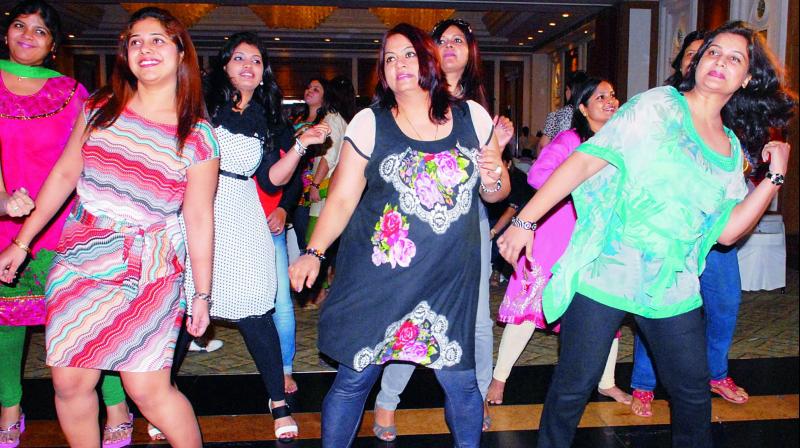 Women take part in a dancing session at a kitty party held in the city