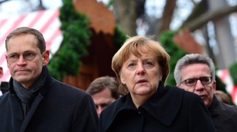 German chancellor Angela Merkel and Berlins mayor Michael Mueller, left, arrive at the Christmas market in Berlin. (Photo: AP)