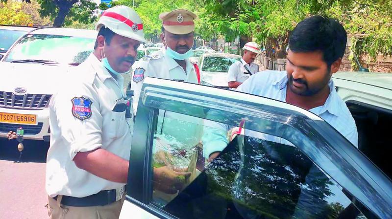 Banjara Hills traffic police removes black tint from the window of a car on Tuesday. 	(Photo: DC)