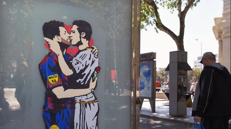 The graffiti on a bus stop in central Barcelona shows the Argentina and Barcelona star embracing and tenderly kissing his Portuguese Real Madrid rival. (Photo: AFP)