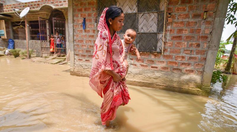 A villager walks through flood water to get to her submerged house, in Hojai on Sunday. (Photo: PTI)