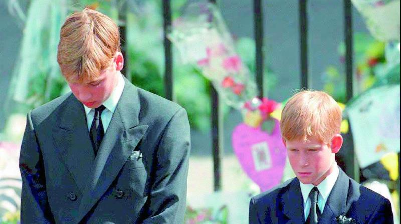 Prince William (L) and Prince Harry bow their heads during the funeral service for Diana on September 6, 1997