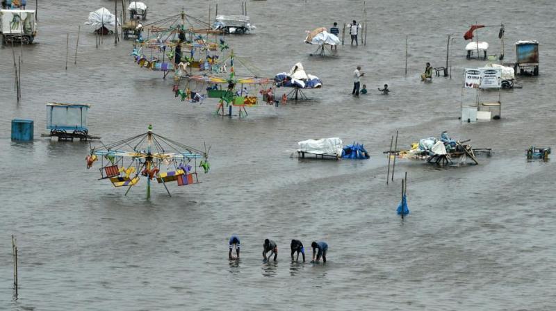 People walk through a flooded area of Marina Beach on the Bay of Bengal coast after heavy rains lashed Chennai for the eighth day. (Photo: AFP)