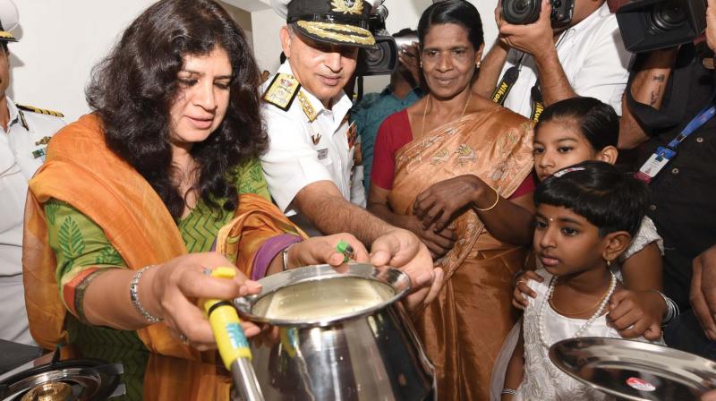President of the Navy Wives Welfare Association (Southern Region) Sapana Chawla gifts a gas stove to the lady of the house as Vice-Admiral Anil Kumar Chawla claps, at the house warming ceremony of V.K. Babu at Muttinakam in Kochi on Saturday.     Image:  DC