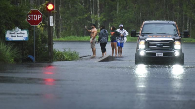 Occupants in a pickup truck get out to look at the rain swollen Julington Creek at the flooded boat ramp on Hood Landing Road by Clarks Fish Camp in Jacksonville, Florida (Photo: AP)