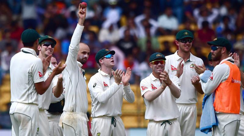 Australias Nathan Lyon celebrates with teammates after taking eight wickets during the first day of the second test match against India at Chinnaswamy Stadium in Bengaluru on Saturday. (Photo: AP)