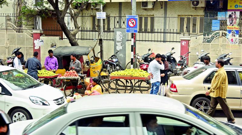 Commuters causing traffic jams as they stop and buy stuff from street vendors in the No Vending zone at Mehdipatnam on Sunday. 	(Photo:  DC)