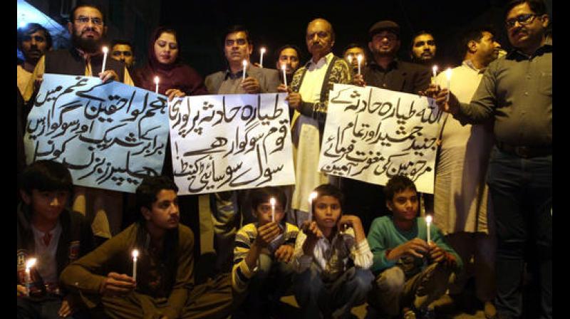 Members of a civil society group hold candles during a vigil for the victims of a plane crash, in Multan, Pakistan. (Photo: A)