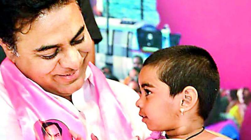 Caretaker minister K.T. Rama Rao holds the grand child of Karimnagar corporator Prabhavathi during a function at TRS Bhavan in Hyderabad on Friday. (Photo: Gandhi)