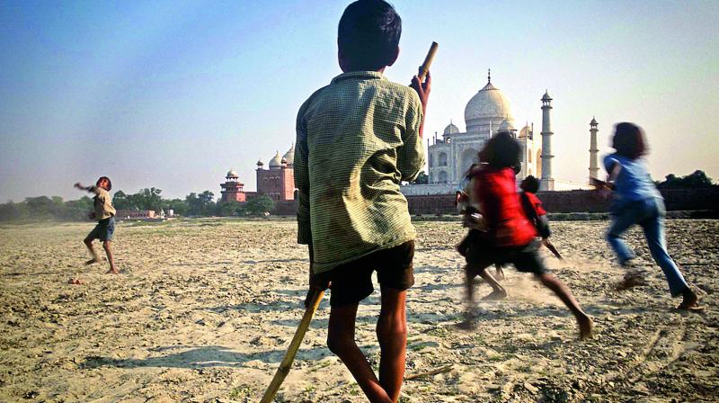 Agra, November 2003. A disabled boy watches the merriment of other children on the sandy bank of the Yamuna river opposite the Taj Mahal, the most recognised symbol of India worldwide.