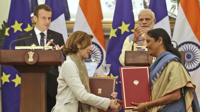 Prime Minister Narendra Modi and French President Emmanuel Macron watch as Defense minister Nirmala Sitharaman exchanges agreement files between India and France on Saturday. (Photo: AP)
