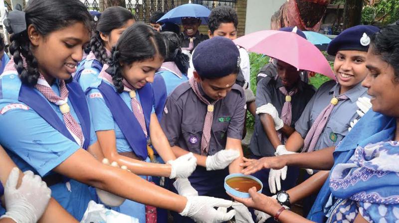 Students applies castor oil on hands to protect themselves from insects prior to a vector control drive at Malappuram collectorate compound.	(Photo: DC0