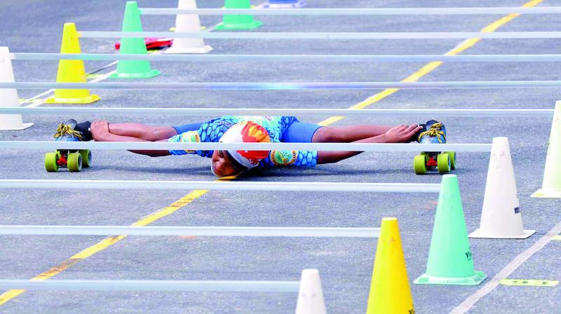 10-year-old G. Devi Sri Prasad squeezes himself down the row of bars to set a world record in limbo skating at Kaza village in Guntur district on Thursday (Photo: DC)