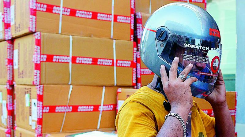 A youngster checks his helmet after  purchasing it from a showroom in Vijayawada on Thursday. (Photo : DC)