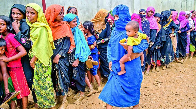 Newly arrived Rohingya women wait for their turn to collect building material for their shelters distributed by aid agencies in Kutupalong refugee camp (Photo: AP)
