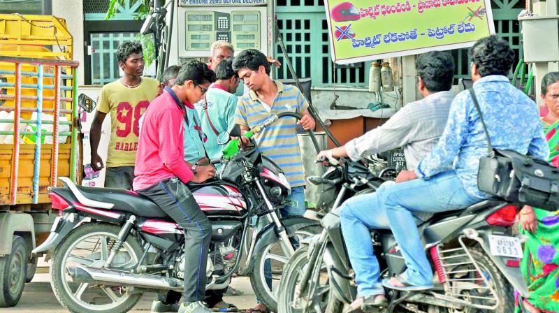 Staff at a petrol refilling station sell petrol to commuters not wearing helmets, even while putting up a banner on the same.