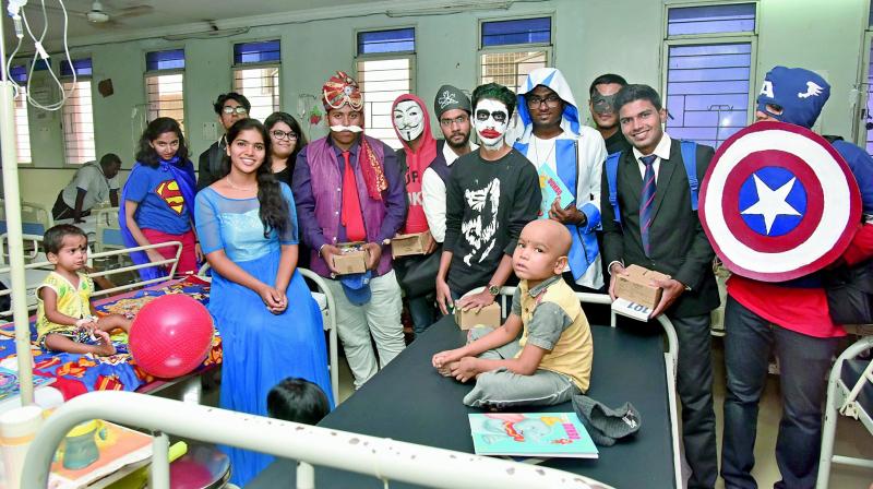 Participants dressed as comic characters with kids at a hospital