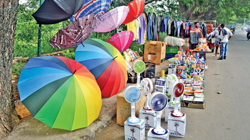 With northeast monsoon round the corner, people purchase umbrellas and rain coats at a roadside shop on New Avadi Road on Wednesday. (Photo: DC)