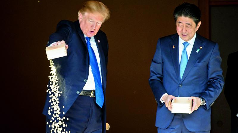US President Donald Trump and Japanese PM Shinzo Abe feed koi fish during a welcoming ceremony in Tokyo on Monday. (Photo: AFP)