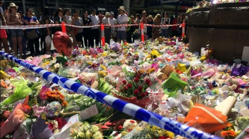 SHARE PICTURE  Visitors lay flowers at a floral tribute on Bourke street in Melbourne on January 22, 2017, after a man went on a rampage in a car. (Photo: AFP)