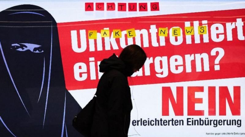 A man walks past an electoral poster by the Committee against Facilitated Naturalization/Citizenship reading \Uncontrolled Naturalisation? No\ featuring a woman wearing a niqab, in a train station in Zurich, on February 7, 2017. (Photo: AFP)