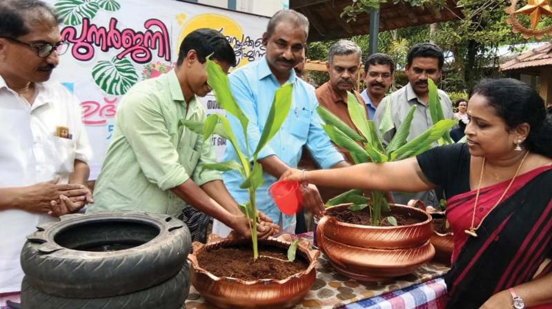 A teacher waters a plant which was planted in a pot made by students out of waste at Girls HSS Koyilandy