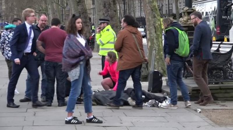 In this image from video, a girl lying on the ground is treated by passers-by on the Embankment near to the Houses of Parliament in London. (Photo: AP)
