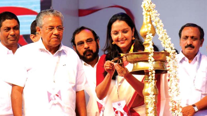 Actress Manju Warrior lighting the traditional lamp during the inauguration of MVR Cancer Centre while Chief Minister Pinarayi Vijayan and M.K. Raghavan MP look on at Valiyassery, Kozhikode on Tuesday.  (Photo: DC)