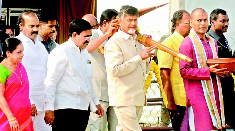 Chief Minister N. Chandrababu Naidu carries a plough for tilling land for laying foundation for construction of TTD Devasthanam at Venkatapalem on Thursday. TTD chairman Putta Sudhakar Yadav, minister P. Narayana and others also seen. (Photo: DC)