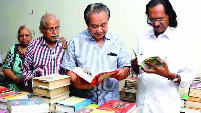 Noted writer U.A. Khader looks at the books exhibited as part of National Book Week celebrations at Police Club in Kozhikode on Monday. Poet P.K Gopi among others looks on. (Photo: DC)