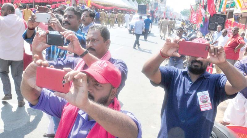 CITU activists capture images of the rally being taken out along the MG Road in front of the Secretariat on Tuesday, expressing solidarity with the two-day all-India general strike. In the background is the huge shamiana covering half the road up to the divider, erected by the organizers in flagrant violation of the court order against blocking roads.  Union leaders took turns, addressing the public meeting of strikers seated under the shamiana. Chief Minister Pinarayi Vijayan and ministers kept off the Secretariat. (Photo: A.V. Muzafar)
