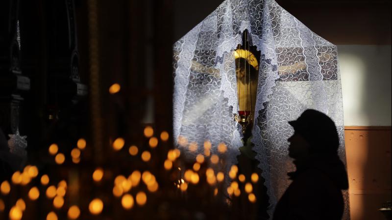 The crucifix is illuminated by sunlight as woman prays during a service on the eve of Easter. (Photo: AP)