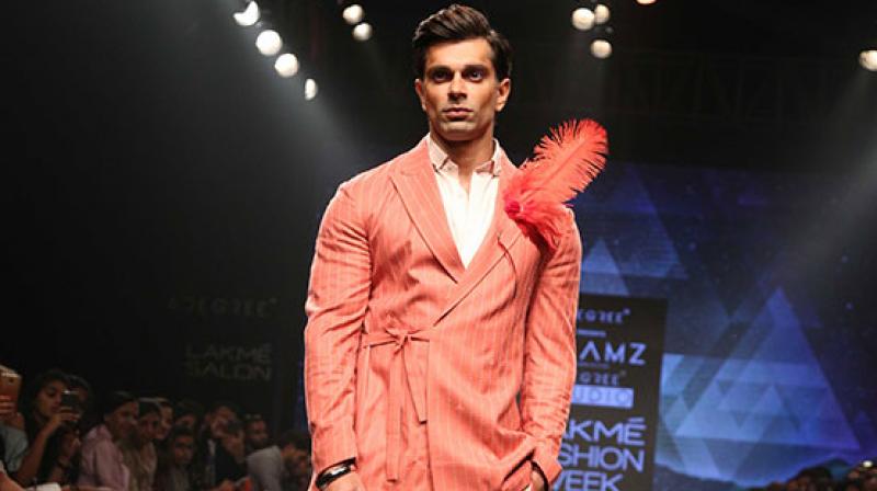 Karan Singh Grover, the showstopper for the designers, sported a bright peach suit with intricate embroidery, accessorised with a bright red feather.