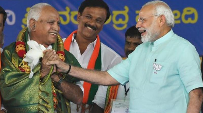 Prime Minister Narendra Modi and BJPs chief ministerial candidate BS Yeddyurappa share a lighter moment during Karnataka election campaign rally at Chamarajanagar. (Photo: PTI)