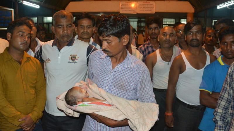 In this Friday, Aug. 11, 2017 photo, a man holds the lifeless body of his child outside Baba Raghav Das Medical College Hospital in Gorakhpur, in the northern Indian state of Uttar Pradesh. (Photo: PTI)