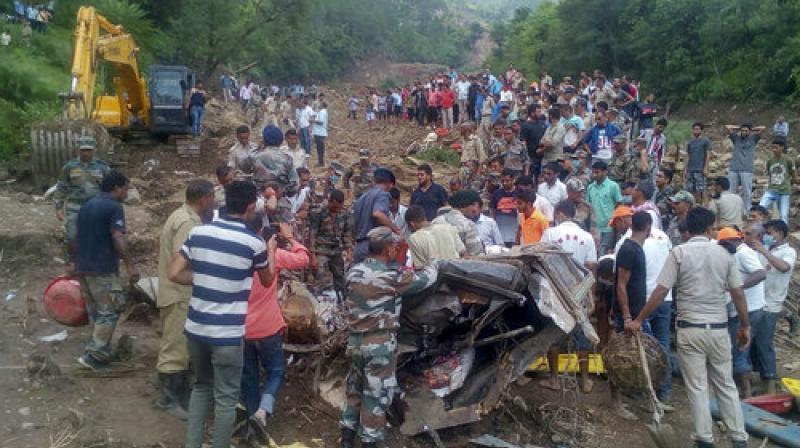 Army soldiers and rescue workers search for bodies of landslide victims even as they try to pull out two buses that were covered in mud after a landslide triggered by heavy monsoon rain in Urla village, Himachal Pradesh state. (Photo: PTI)