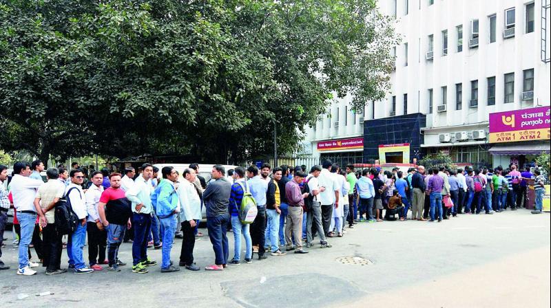 People queue up outside an ATM to withdraw money in New Delhi on Monday.