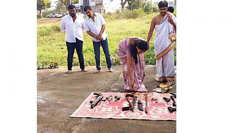 A family member of Jaya Karnataka chief Muthappa Rai performs puja for guns and other lethal weapons, as  Rai (second from left) looks on