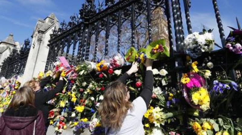 People place flowers outside Britains parliament in London, Saturday March 25, 2017, for the victims of the Westminster attack on Wednesday. Khalid Masood killed four people and left more than two dozen hospitalized, including some with what have been described as catastrophic injuries. The Islamic State group claimed responsibility for the attack. (AP Photo/Kirsty Wigglesworth)