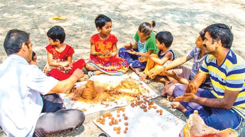 Volunteers  along with kids prepare seed balls.