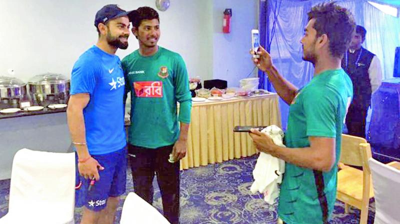 A Bangladesh player takes a photograph with Virat Kohli.(Photo: BCCI)