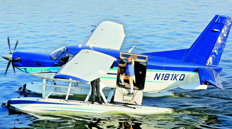Prime Minister Narendra Modi waves to the crowd before soaring into the clear Ahmedabad sky on a seaplane from the Sabarmati river, marking a dramatic end to a gruelling election campaign, on Tuesday. The second phase polling in Gujarat takes place on Thursday. (Photo: PTI)