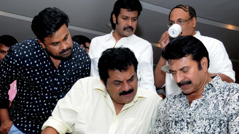 WE ARE IN NEWS: AMMA general secretary Mammooty along with actors Mukesh, Manoj K. Jayan and Dileep watch TV coverage of AMMAs annual general body meeting on Mammootys mobile on Thursday. (Photo: ARUN CHANDRABOSE)